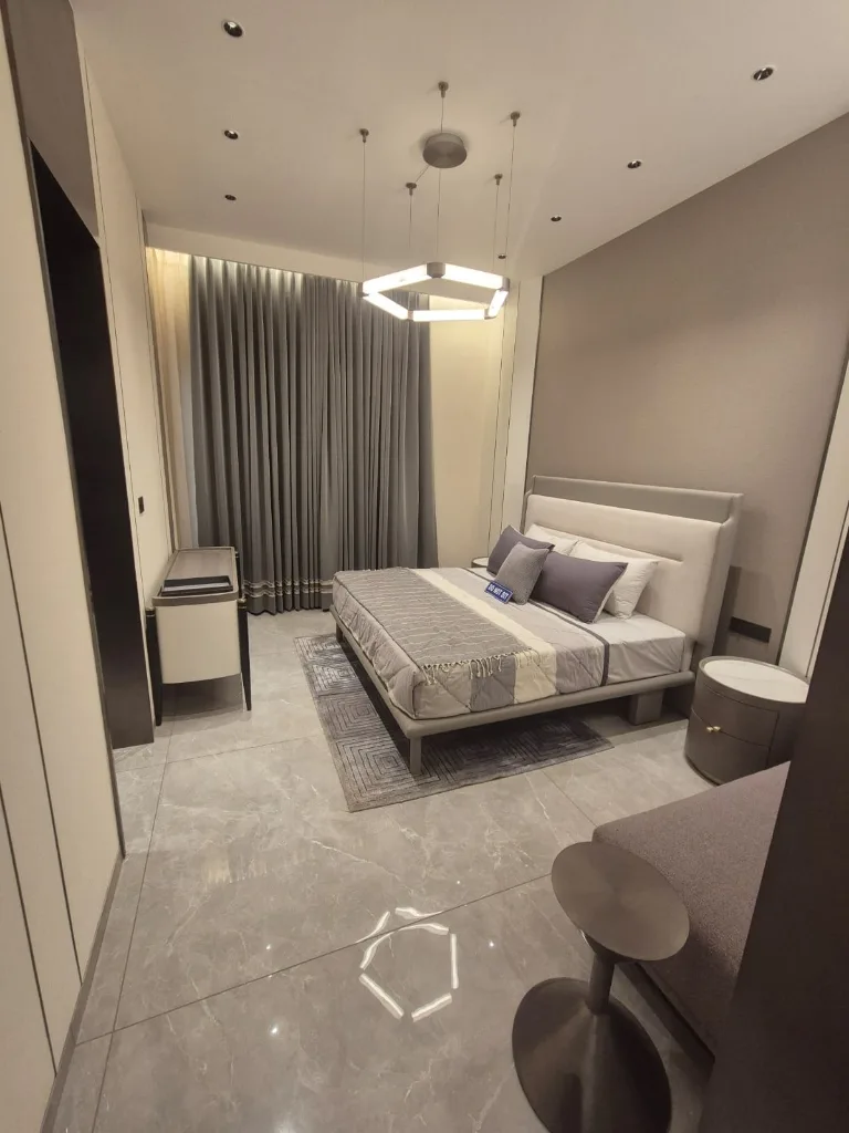 Ultra-luxury bedroom interior in Medallion Aurum featuring a modern king-size bed with grey and white upholstery and warm ambient lighting